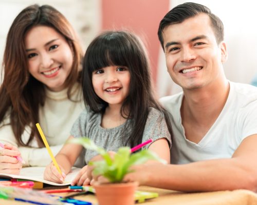 cute black hair child female daughter homework and laugh together with parent in living room house concept